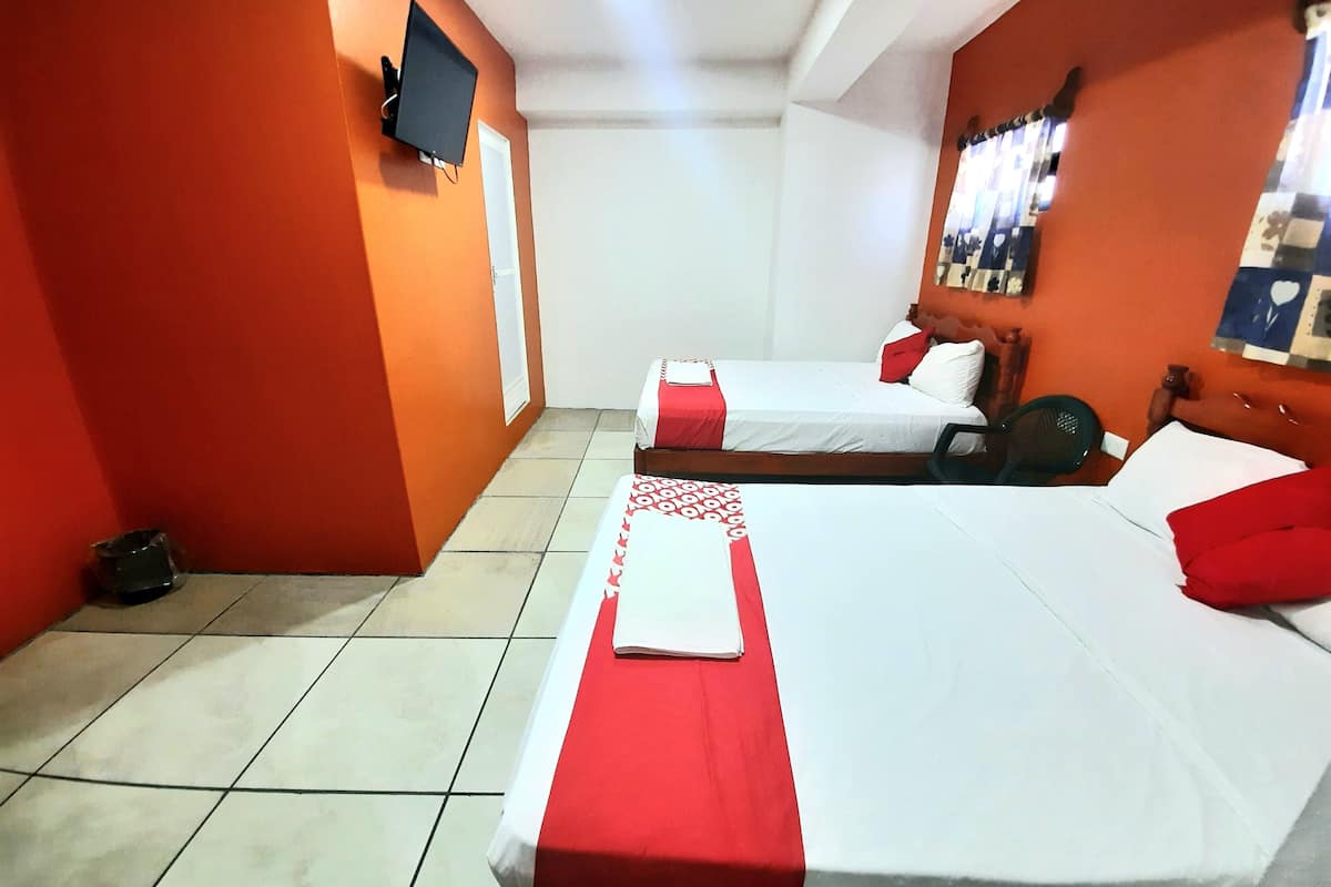 Habitación de hotel con dos camas, un televisor montado en la pared y un espejo con fotografías.