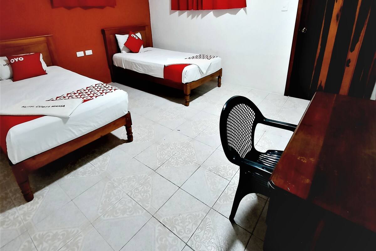 Habitación de hotel con dos camas, un escritorio, una silla, un armario y un equipo de aire acondicionado.
