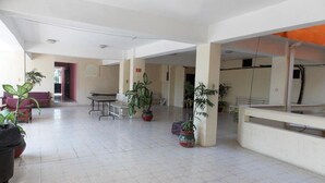 A spacious indoor area with tiled flooring, several potted plants, and a few seating arrangements. - Hotel Costa Maria (Ciudad del Carmen)