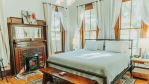 A bedroom with a large bed, a wooden bench, a fireplace, and a mirror above it. - Alpine Bed and Breakfast (Alpine)