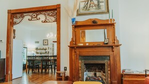 A room with a wooden fireplace, a dining area with chairs and a table, and a colorful bench. - Alpine Bed and Breakfast (Alpine)