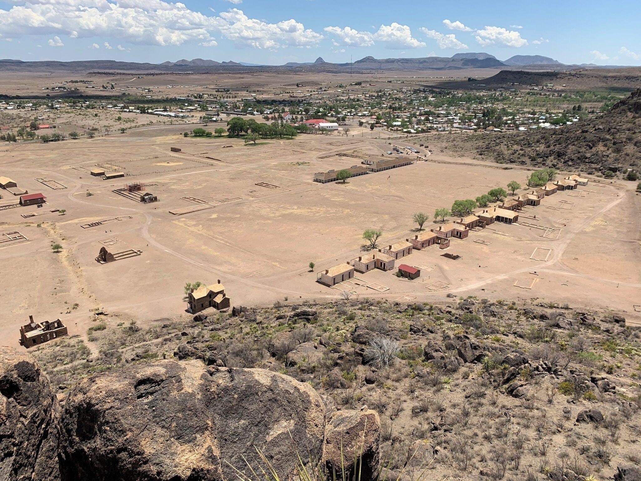 A desert landscape with scattered buildings, including a large open area with a few structures and a small settlement in the distance.