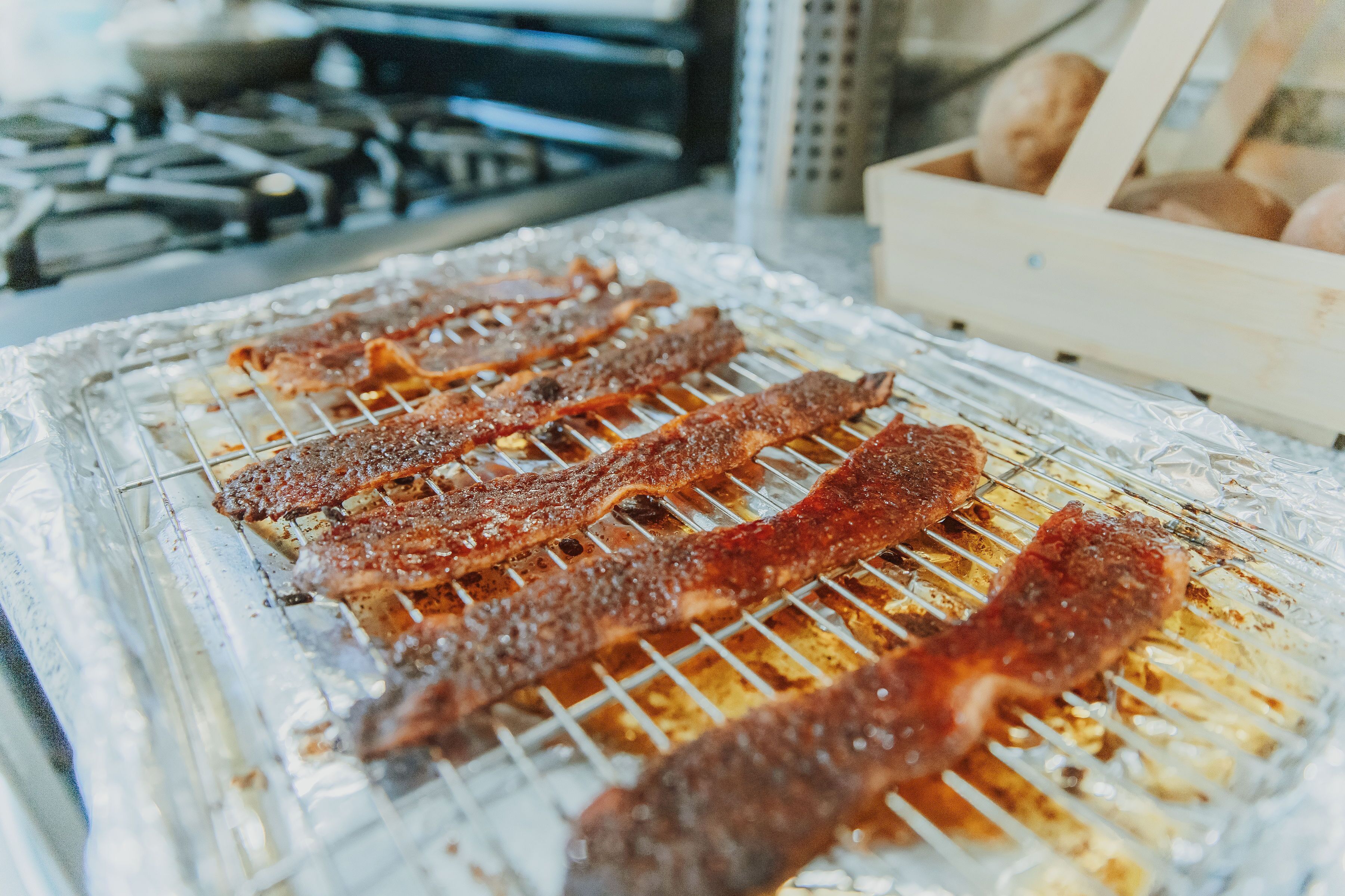 Bacon being grilled on a wire rack over foil.