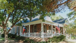 A two-story house with a porch, brick exterior, and an American flag. - Alpine Bed and Breakfast (Alpine)