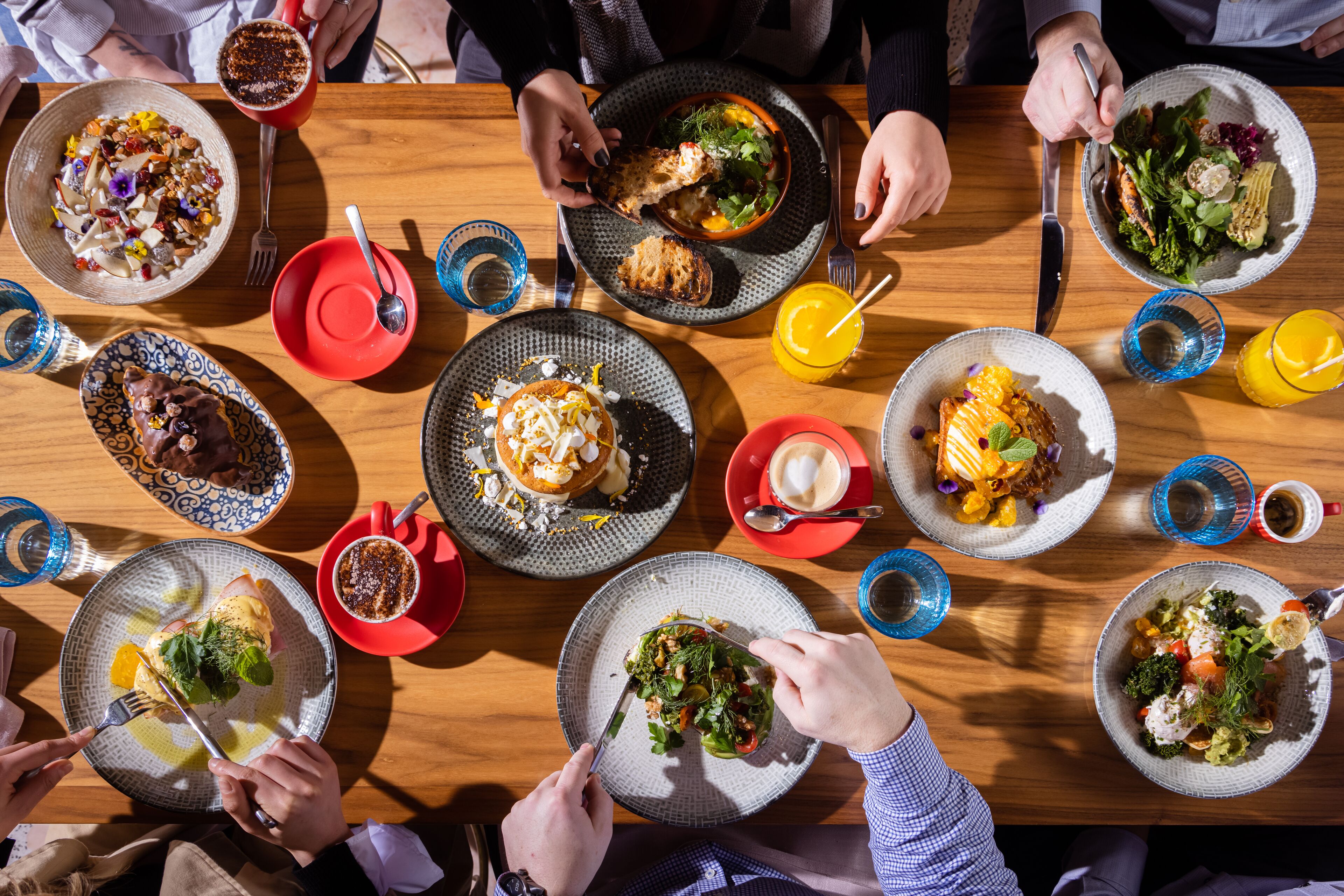 Una mesa de comedor con varios platos de comida, cubiertos y vasos.