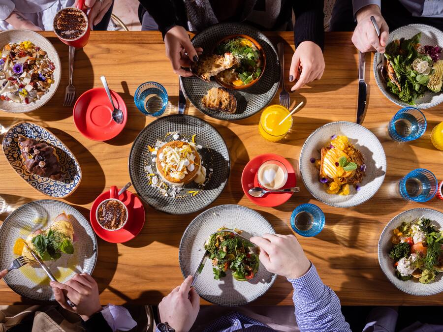 Una mesa de comedor con varios platos de comida, cubiertos y vasos.