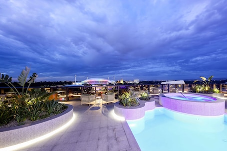 Una piscina al aire libre, sombrillas, sillones reclinables de piscina