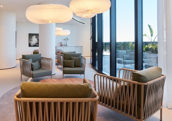 A modern interior with wicker furniture, large windows, and a view of the outdoors.