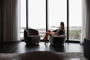 A room with a large window, a sofa, and a chair. - Eos by SkyCity (Adelaide)