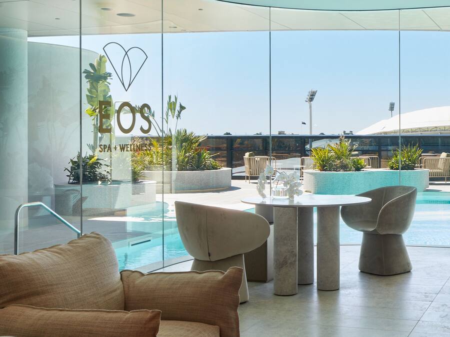Un moderno espacio de spa con pared de vidrio, asientos al aire libre y una piscina.