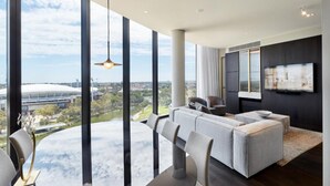 Una sala de estar moderna con un gran ventanal, un sofá, una mesa de comedor y un televisor.