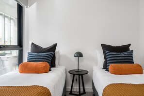 Ein Hotelzimmer mit zwei Betten, einem kleinen Tisch und einer Lampe.