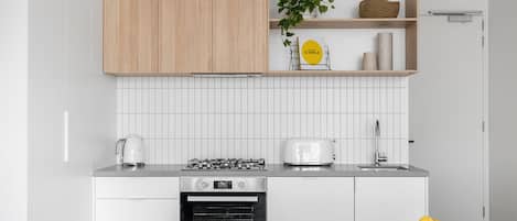 A modern kitchen with white cabinetry, a gas stove, a toaster, and a bowl of lemons on the table.