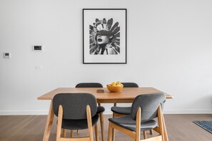 Ein Essbereich mit einem Holztisch, vier grau gepolsterten Stühlen und einem schwarzen und weißen Bild in einem Rahmen an der Wand.