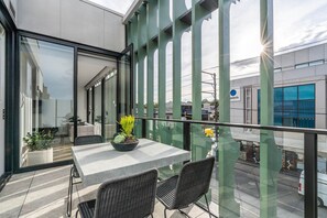 Een balkon met een tafel en stoelen, een potplant en uitzicht op de straat.