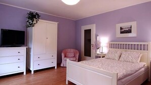 Een slaapkamer met een bed, een kledingkast, een televisie en een stoel.