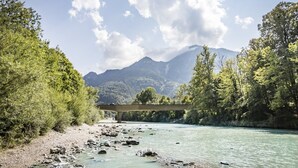 Un río con un puente, rodeado de árboles y montañas.