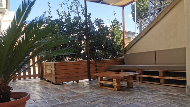 An outdoor patio area with a wooden bench, a table, and a potted plant. - DOMUS LEVI APARTMENT (Matera)