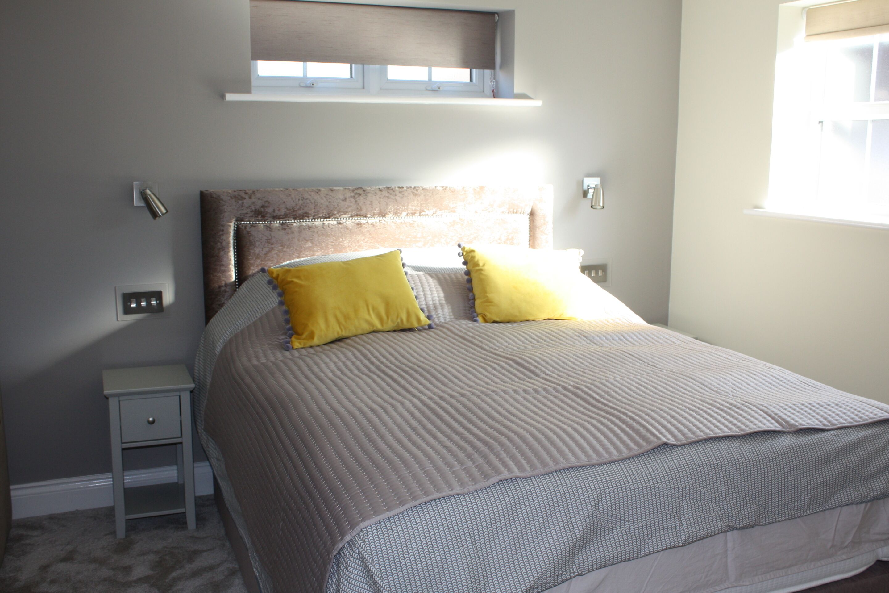 Een slaapkamer met een bed, nachtkastje en een raam.