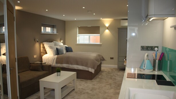 A bedroom with a bed, bedside table, and a small window. - Frinton Escapes (Frinton-on-Sea)