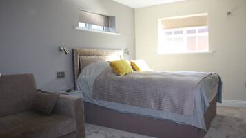 A bedroom with a bed, a nightstand, a lamp, a window, and a couch.