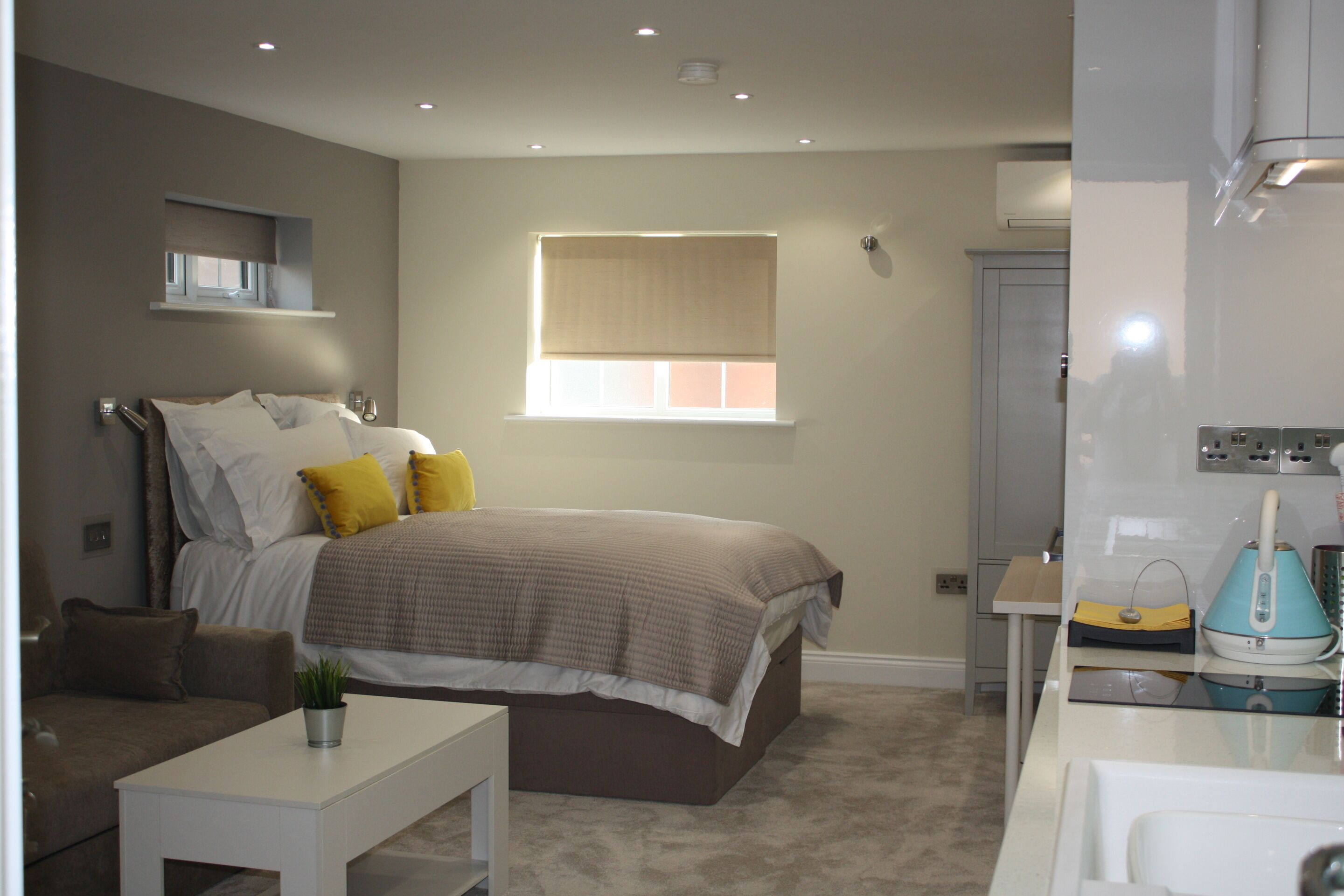 A bedroom with a bed, bedside table, and a window with blinds.