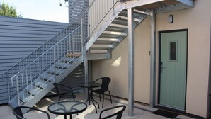 A staircase leading to an upper level, outdoor seating with chairs and tables, and a green door. - Frinton Escapes (Frinton-on-Sea)