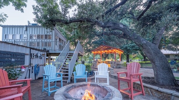 An outdoor seating area with Adirondack chairs, a fire pit, and a covered patio. - Luxury WATERFRONT home with HEATED POOL AND SPA Sleeps 28+ (Kingsland)
