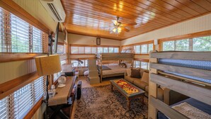 A cozy room with a wooden ceiling, bunk beds, a sofa, and a table. - Luxury WATERFRONT home with HEATED POOL AND SPA Sleeps 28+ (Kingsland)