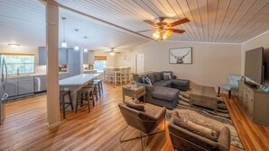 A spacious living area with a dining table, sofas, and a TV. - Luxury WATERFRONT home with HEATED POOL AND SPA Sleeps 28+ (Kingsland)