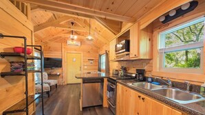 L’intérieur d’un chalet en bois comprend une cuisine, un coin repas et une fenêtre donnant sur un paysage agréable.