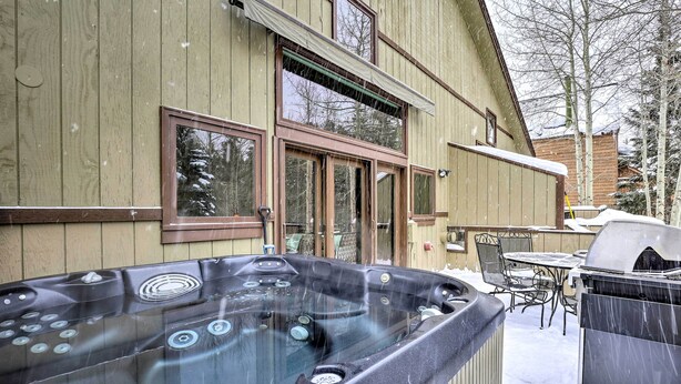 Een bubbelbad in een besneeuwde omgeving, met een houten huis op de achtergrond.