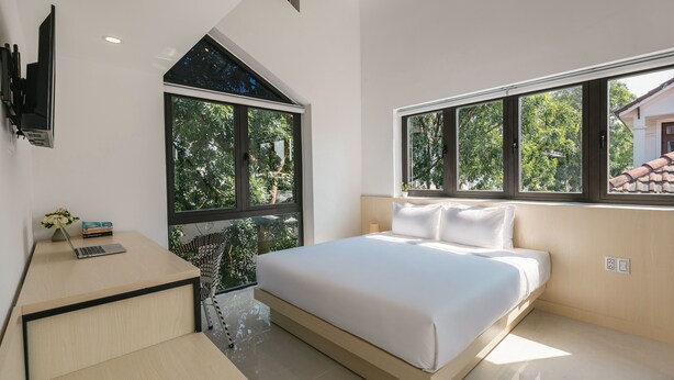 A modern bedroom with a large bed, a desk, and a TV mounted on the wall. - Bespoke Villa Hoi An (Da Nang)