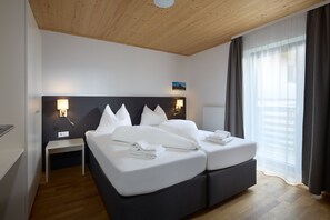 A modern hotel room with a large bed, bedside tables, and a view of the outdoors.