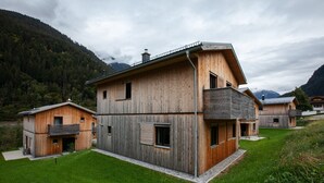 Une maison moderne en bois, dotée d’un toit en pente, de grandes fenêtres et d’un balcon.
