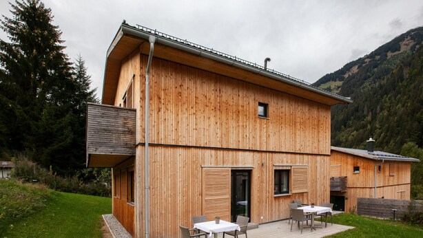 Une cabane en bois avec une terrasse, une petite fenêtre et une porte.