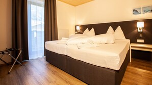 Une chambre d’hôtel avec un grand lit, une table de chevet, une lampe, une fenêtre avec des rideaux et un plafond en bois.