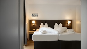 A double bed with white linens and pillows, two bedside lamps, a small bedside table, and a framed picture on the wall. - 4513 Alpin 13 (St. Gallenkirch)