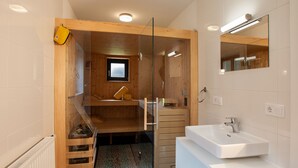 Een moderne badkamer met een houten inrichting, een douchecabine van glas en een witte wastafel.