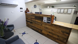 Een receptiegedeelte met een houten receptiebalie, een klok en een blauw pijlpaviljoen op de vloer.