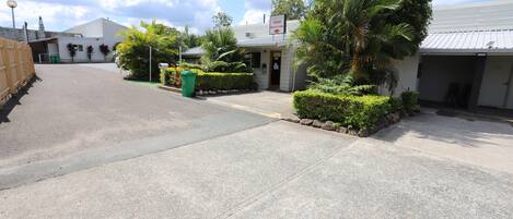 A motel with a reception desk, a parking area, and a building with a metal roof.