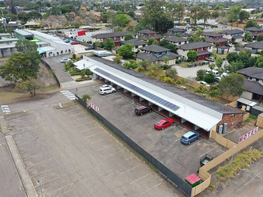 Ein Motel mit einem langgestreckten Gebäude mit flachem Dach, einem Parkplatz und mehreren parkenden Autos davor.
