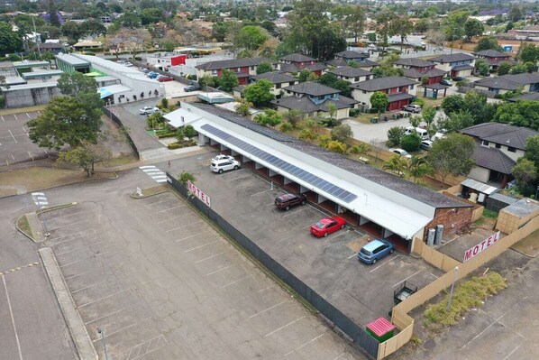 Un motel con un edificio de techo plano y amplio, un estacionamiento y varios coches aparcados en la entrada.