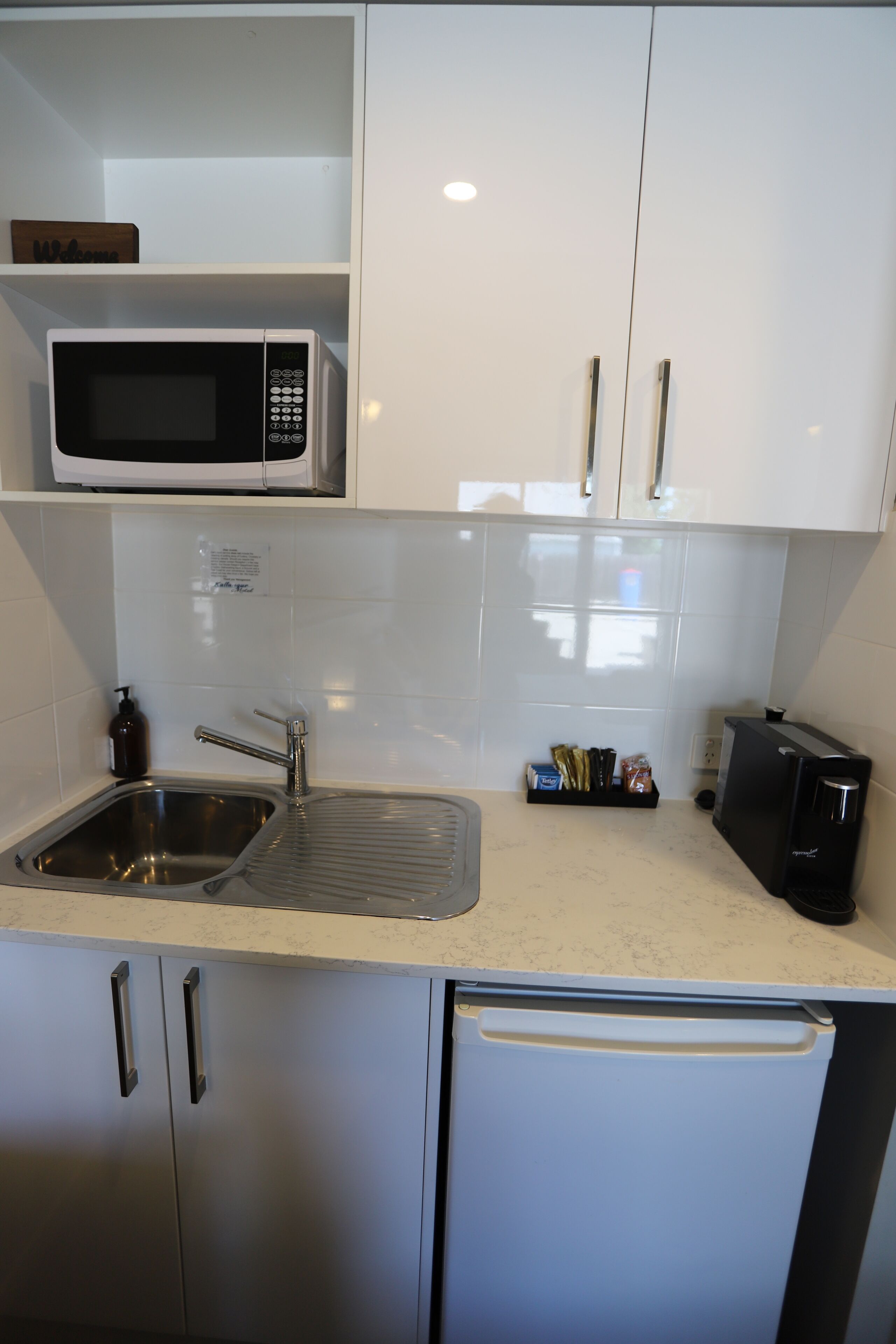 A modern kitchen with stainless steel appliances, a sink, and white cabinetry.