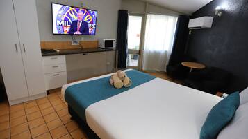 A hotel room with a bed, a television, a microwave, and a small table.