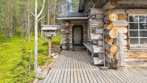 A log cabin with a wooden deck, a small porch, and a window with a 'B' sign. - Hankipolku 7b / ukuli by Interhome (Ylläsjärvi)