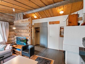 A log cabin interior with a living area, a television, a desk with a computer, and a fireplace.