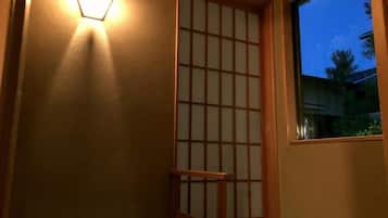 Een kamer met een traditionele schuifdeur, een houten bank en een raam met uitzicht.