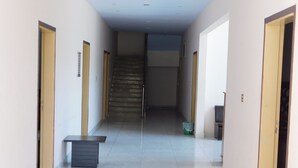 A hallway with doors on both sides, a staircase in the center, and a trash bin in the middle. - Pine View hotel and Restaurant (Balakot)