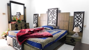 A bedroom with a bed, a dresser, a mirror, and decorative panels on the walls. - Pine View hotel and Restaurant (Balakot)